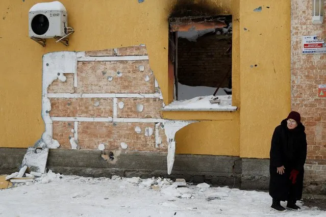 A local woman walks next to a wall of a residential building, heavily damaged during Russian invasion, from which a group of people tried to steal the work of street artist Banksy, in the town of Hostomel, Kyiv region, Ukraine on December 3, 2022. (Photo by Valentyn Ogirenko/Reuters)