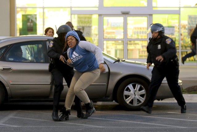 Baltimore police officers chase down, tackle and arrest a woman after she and other looters ran from a “Deals” store (rear) with merchandise during clashes between rioters and police after the funeral of Freddie Gray in Baltimore, Maryland April 27, 2015. (Photo by Jim Bourg/Reuters)
