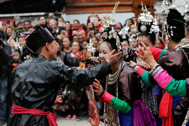 An ethnic “Kam” (also known as Dong) man touches the face of his bride during a traditional wedding ritual known as the “steal the chicken at the drum tower”. “It was later that people realised this was not the correct way to marry. Now we have the freedom to marry whom we want”, he said. (Photo by Tyrone Siu/Reuters)