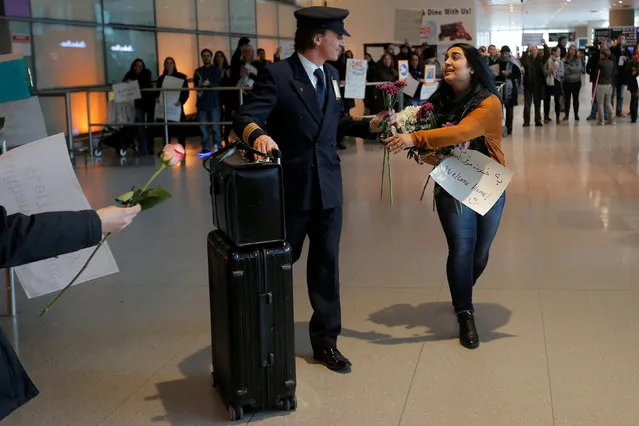 An opponent of U.S. President Donald Trump's executive order travel ban hands a flower to a member of a Lufthansa flight crew at Logan Airport in Boston, Massachusetts, U.S. February 3, 2017.  The Lufthansa flight carried several Boston area college students who had previously been denied travel under the travel ban. (Photo by Brian Snyder/Reuters)