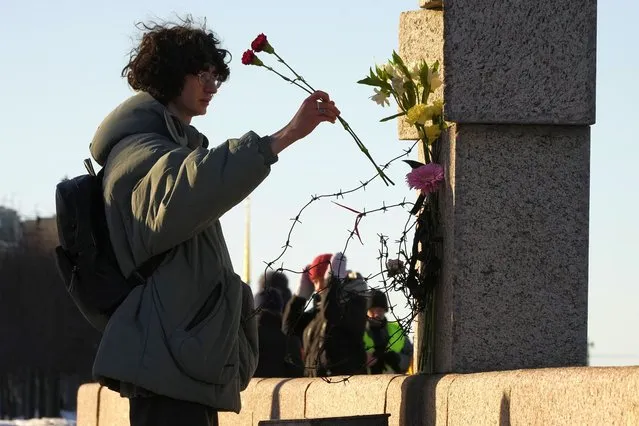 A woman places flowers as people pay tribute to Alexei Navalny at the Memorial to Victims of Political Repression in St. Petersburg, Russia, Sunday, February 18, 2024. Russians across the vast country streamed to ad-hoc memorials with flowers and candles to pay tribute to Alexei Navalny, the most famous Russian opposition leader and the Kremlin's fiercest critic. Russian officials reported that Navalny, 47, died in prison on Friday. (Photo by Dmitri Lovetsky/AP Photo)