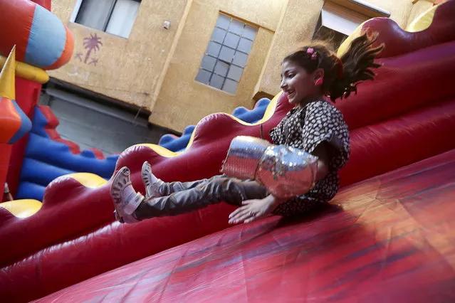 Nour, a 9 year-old girl, who lives in the rebel-held neighborhood of Jobar in Damascus, plays on an inflatable slide in the neighboring suburb of Hamouriyeh, where they came to celebrate the Muslim holiday of Eid al-Fitr, which marks the end of the holy month of Ramadan, Syria July 18, 2015. (Photo by Bassam Khabieh/Reuters)