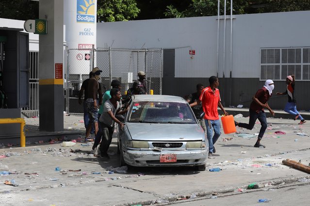 Men push a car from a gas station ransacked by people angry after the station refused to distribute fuel amid a nationwide shortage, in Port-au-Prince, Haiti on November 4, 2021. (Photo by Ralph Tedy Erol/Reuters)