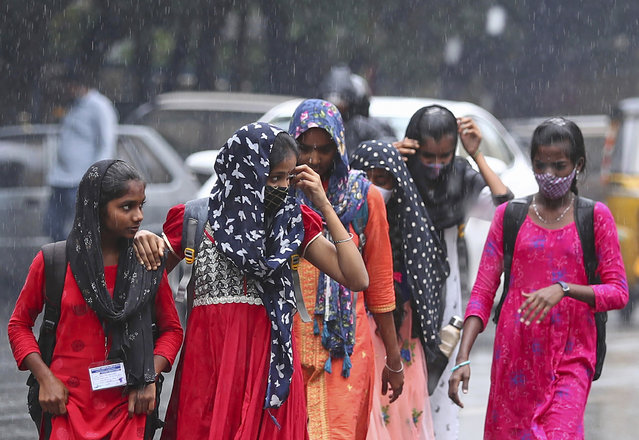 People walk in the rain in Hyderabad, India, Saturday, November 20, 2021. (Photo by Mahesh Kumar A./AP Photo)