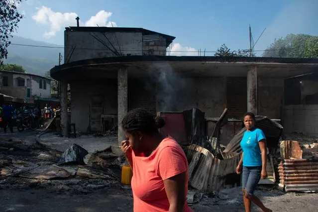 A woman cries as she walks near her husband's shop that was set on fire by armed gang members in Port-au-Prince, Haiti, on Thursday, March 7, 2024. Gangs control 80% of the Haitian capital, the UN estimates, and continue to fight for the rest. Haiti's government declared a state of emergency on Sunday. (Photo by Clarens Siffroy/AFP Photo)