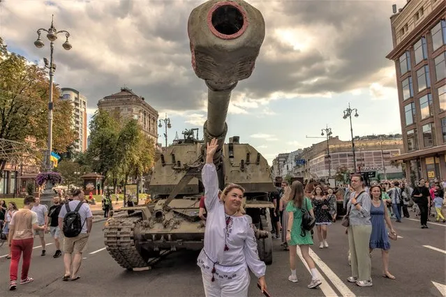 A woman wearing traditional Ukrainian clothes poses for photographs in front of a destroyed Russian armored military vehicle displayed in main street Khreshchatyk Street on Ukraine's Independence Day in Kyiv, on August 24, 2023, amid the Russian invasion of Ukraine. (Photo by Roman Pilipey/AFP Photo)