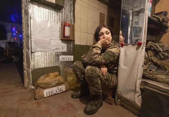 A Ukrainian soldier rests near a fighting position on the line of separation from pro-Russian rebels near Katerinivka, Donetsk region, Ukraine, Tuesday, December 7, 2021. When Russia annexed Ukraine's Crimean Peninsula in 2014 and threw its support behind separatists in the country's east, Kyiv's underfunded and disorganized armed forces struggled to respond. Now, amid fears that a Russian troop buildup near Ukraine's border could signal a possible attack, military experts say there would be stronger resistance but that Ukraine would be well short of what it needs to counter Russia's overwhelming land, sea and air superiority. (Photo by Andriy Dubchak/AP Photo)