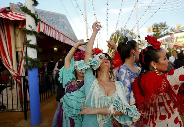 Women wearing sevillana dresses dance during the traditional Feria de Abril (April fair) in the Andalusian capital of Seville, southern Spain, April 13, 2016. (Photo by Marcelo del Pozo/Reuters)
