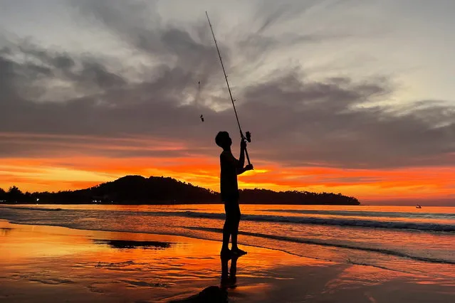 A boy fishes during sunset at Bang Tao beach in Phuket, Thailand, December 6, 2021. (Photo by Jorge Silva/Reuters)