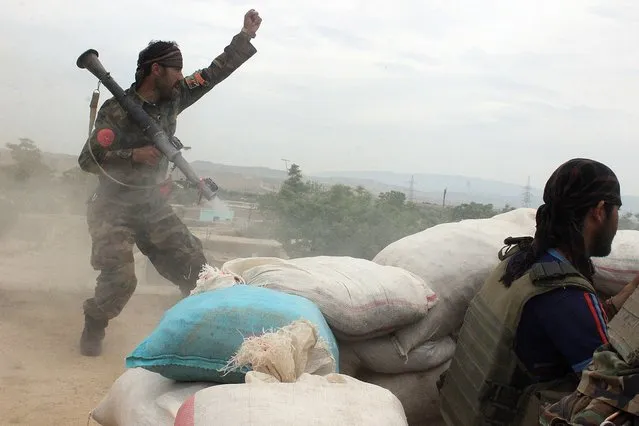 An Afghan National Army soldier, left, shouts against the Taliban, after firing a rocket towards Taliban positions, on the outskirts of Kunduz, northern Afghanistan, Saturday, April 16, 2016. Officials say Afghan forces have repelled a Taliban assault on the northern city of Kunduz, which the insurgents had briefly seized last year. (Photo by Najim Rahim/AP Photo)