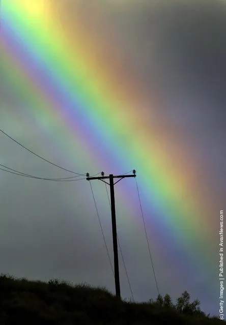 A rainbow appears in a stormy sky over a power line near San Fernando