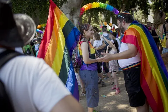 People participate the annual Gay Pride Parade in Tel Aviv, Israel, Friday, June 12, 2015. Thousands of bare-chested muscular men, drag queens in heavy makeup and high heels, women in colorful balloon costumes and others partied at Tel Aviv's annual gay pride parade on Friday, the largest event of its kind in the region. (AP Photo/Ariel Schalit)