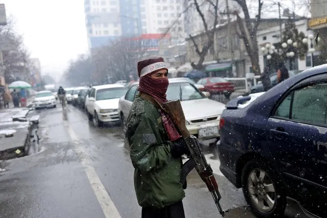 A Taliban fighter stands guard at a checkpoint during a snowfall in Kabul, Afghanistan, January 3, 2022. (Photo by Ali Khara/Reuters)