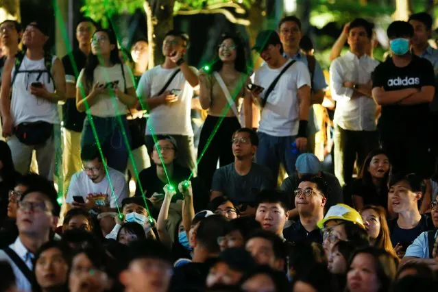 People aim laser pointers at the facade of the Hong Kong Space Museum during a flash mob staged to denounce the authorities' claim that laser pointers were offensive weapons in Hong Kong, China, August 7, 2019. Protesters say Keith Fong, a student union leader from Baptist University, was unlawfully arrested by several plainclothes police for buying laser pointers on the grounds that he possessed offensive weapons. (Photo by Thomas Peter/Reuters)