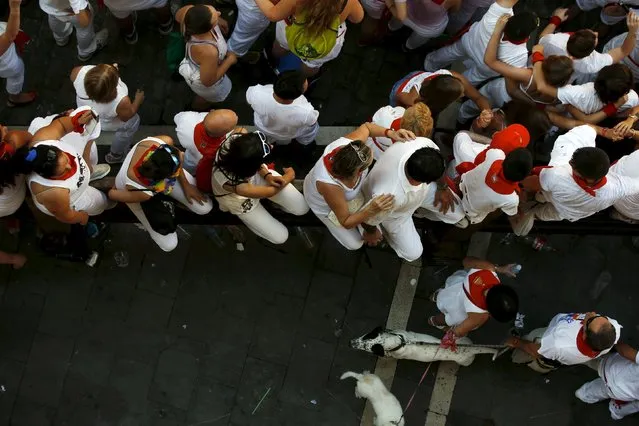 Revellers sit on a bull run fence during the traditional Riau-Riau dance from the town hall to the Saint Fermin Chapel at San Lorenzo church on the first day of the San Fermin Festival in Pamplona, Spain, July 6, 2015. (Photo by Susana Vera/Reuters)