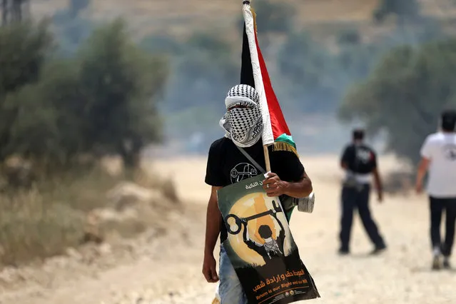 A masked protester holds a Palestinian flag during clashes with Israeli troops at a protest ahead of Nakba day, in the West Bank village of Bilin near Ramallah May 13, 2016. (Photo by Mohamad Torokman/Reuters)