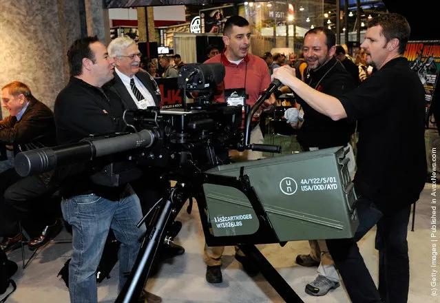 Attendees look at a belt-fed automatic 40mm HK GMG (grenade machine gun) with a ballistic fire control computer attached at the Heckler & Koch booth