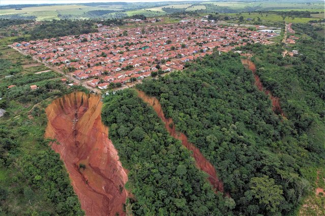 Aerial view of erosions in Buriticupu, Maranhao state, Brazil, taken on April 21, 2023. An unusual phenomenon caused by a lack of urban planning and aggressive deforestation is driving Buriticupu, a small town in Brazil's impoverished northeastern state of Maranhao, towards gradual collapse, experts say. The city of 70,000 is suffering from the advance of “vocorocas” – “torn earth” in the indigenous Tupi-Guarani language – erosions that begin as small cracks in the ground and grow into large craters that, seen from the air, look like advancing canyons swallowing up chunks of the town. (Photo by Nelson Almeida/AFP Photo)