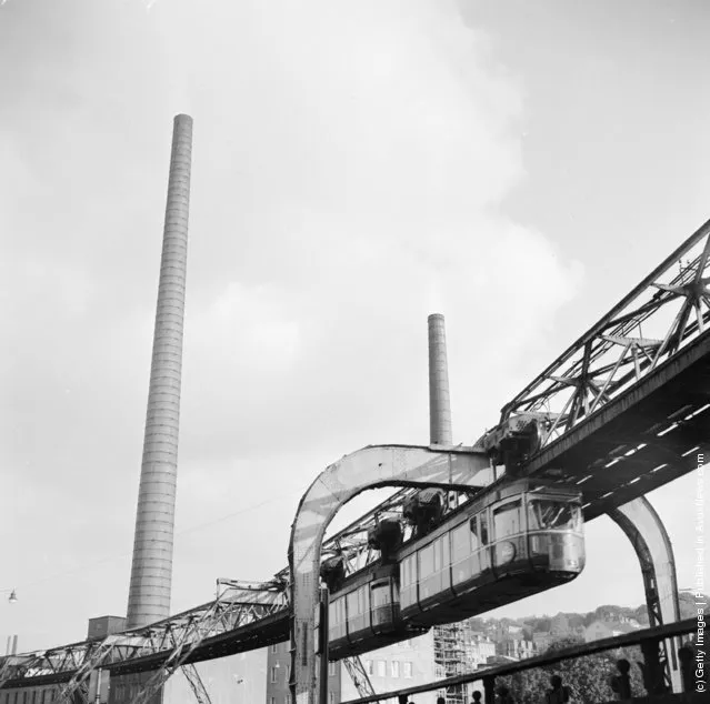 1956:  A hanging monorail train moves along the seven mile Wuppertal Monorail System in Germany, just above the stream of traffic