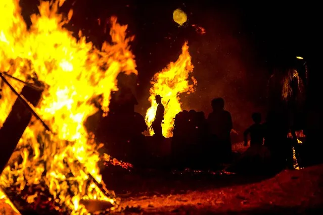 Ultra-Orthodox Jews stand next to bonfires during Lag Ba'Omer celebrations to commemorate the end of a plague said to have decimated Jews in Roman times, in Bnei Brak, Israel, on May 17, 2014. (Photo by Oded Balilty/Associated Press)