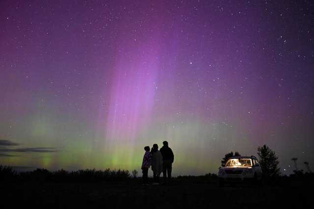 The Aurora Borealis, also known as the "Northern Lights", illuminate the sky as people gather to watch the annual Perseid meteor shower near the village of Borodinka in the Omsk region, Russia on August 13, 2024. (Photo by Alexey Malgavko/Reuters)