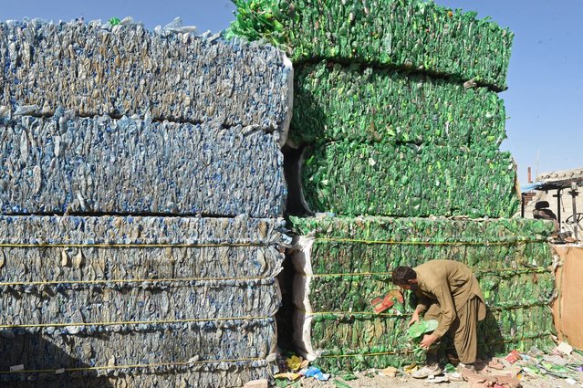 A labourer works beside the pile of used plastic bottles at a recycling factory in Quetta on September 8, 2024. (Photo by Banaras Khan/AFP Photo)