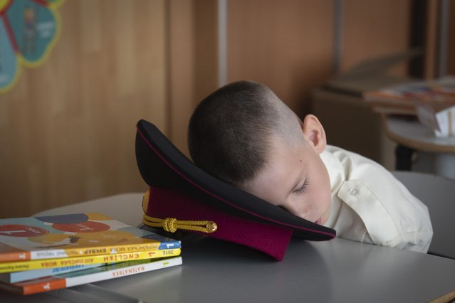 A young cadet takes a nap at the first lesson in a cadet lyceum on the first day at school in Kyiv, Ukraine, Monday, September 2, 2024. Children and students went to school despite the fact that Kyiv was hit by massive Russian missile barrage early in the morning, causing fires, damaged buildings and infrastructure objects. (Photo by Efrem Lukatsky/AP Photo)