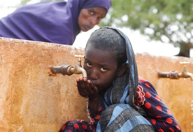 Somali displaced girl Sadia Ali, 8, drinks water from a tap at the Kaxareey camp for the internally displaced people in Dollow, Gedo region of Somalia on May 24, 2022. (Photo by Feisal Omar/Reuters)