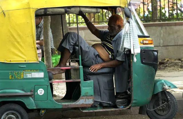 An auto rickshaw driver exhausted from intense heat rests in his vehicle, in New Delhi, Thursday, May 19, 2022. The intense heat wave sweeping through South Asia was made more likely due to climate change and it is a sign of things to come. An analysis by international scientists said that this heat wave was made 30-times more likely because of climate change, and future warming would make heat waves more common and hotter in the future. (Photo by Manish Swarup/AP Photo)
