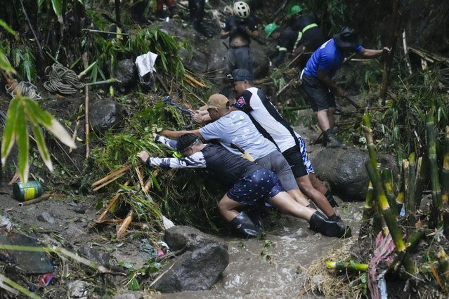 Volunteers and rescuers move debris as they search for bodies of missing residents believed to be buried under a landslide caused by heavy rains from Tropical Storm Yagi, locally called Enteng, swept their homes in San Luis village, Antipolo city, Rizal province, Philippines on Tuesday, September 3, 2024. (Photo by Aaron Favila/AP Photo)