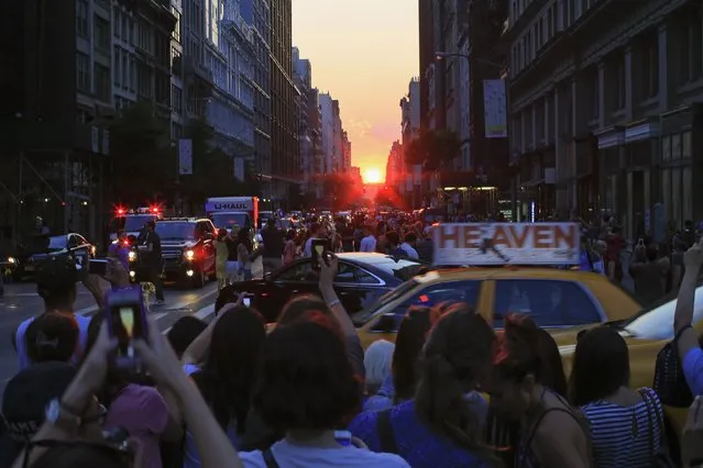 People take pictures at sunset during the bi-annual occurrence “Manhattanhenge” in New York July 11, 2014. Manhattanhenge, coined by astrophysicist Neil deGrasse Tyson, occurs when the setting sun aligns itself with the east-west grid of streets in Manhattan, allowing the sun to shine down all streets at the same time. (Photo by Eduardo Munoz/Reuters)