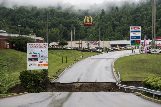 People and vehicles are stranded at Crossing Annex Shops in Elkview , W.Va., Friday, June 24, 2016, after a bridge collapsed due to heavy rains and flooding the night before. (Photo by Sam Owens/Charleston Gazette-Mail via AP Photo)