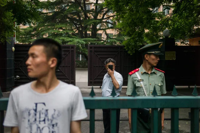 A North Korean delegate (back C) takes pictures of journalists gathered to cover a stand-up press conference by a North Korean Talks representative at the gate of North Korea's Embassy in Beijing on June 23, 2016. North Korean leader Kim Jong-Un hailed the successful test of a powerful new medium-range missile as a direct threat to US military bases across the Pacific, as the UN Security Council met late on June 22 to consider its response. (Photo by Fred Dufour/AFP Photo)