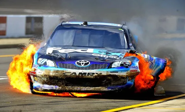 Denny Hamlin drives down pit road with his car engulfed in fire during the NASCAR Sprint Cup Series Quicken Loans 400 race at Michigan International Speedway in Brooklyn, Michigan on June 17, 2012