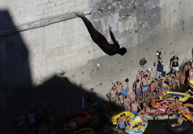 Spectators watch as a diver jumps from the Old Mostar Bridge during 451th traditional annual high diving competition, in Mostar, 140 kms south of Bosnian capital of Sarajevo, Sunday, July 30, 2017. Total of 41 divers from Bosnia and neighbouring countries competed diving from 25 meters high Old Mostar Bridge into the Neretva river. (Photo by Amel Emric/AP Photo)