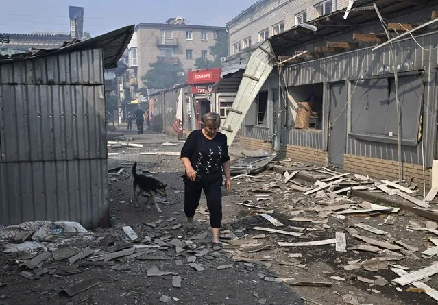 A woman passes by destroyed shops on a local market after a rocket attack in the Ukrainian town of Sloviansk, on July 3, 2022, amid the Russian invasion of Ukraine. (Photo by Genya Savilov/AFP Photo)