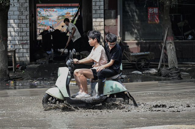 Local residents ride a scooter through a muddy street in the aftermath of flooding from heavy rains in Zhuozhou city, in northern China's Hebei province on August 9, 2023. China's capital has been hit by record downpours in recent weeks, damaging infrastructure and deluging swaths of the city's suburbs and surrounding areas. In Hebei province, which neighbours Beijing, 15 were reported to have died and 22 were missing. (Photo by Jade Gao/AFP Photo)