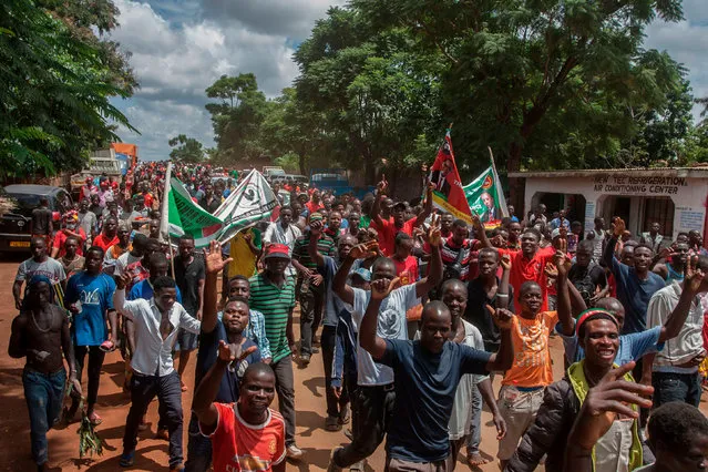 Political supporters carry flags of the Malawi Congress Party (MCP) and United Transformation Movement (UTM) on their way to an event of a signed an electoral alliance of the two parties in Lilongwe on March 19, 2020. On March 19, 2020, the country's largest opposition, the Malawi Congress Party (MCP) and United Transformation Movement (UTM) signed an electoral alliance at a ceremony attended by thousands of supporters in the capital Lilongwe. (Photo by Amos Gumulira/AFP Photo)