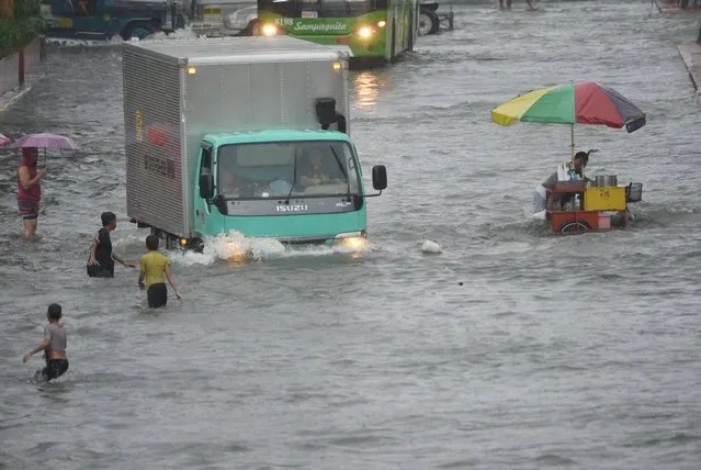 Residents and motorists manoeuver along a flooded main street in Manila on September 12, 2017, after tropical depression locally codenamed “Maring”, hit the eastern town of Mauban before moving northwest across the main island of Luzon and passing just beside Manila, the government weather station said. At least three people died and six were missing after a major storm caused widespread flooding in and around the Philippine capital on September 12, forcing schools, government offices and businesses to shut down. (Photo by Ted Aljibe/AFP Photo)