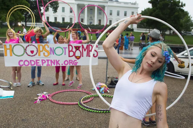 Keely Madison (R), alongside other demonstrators with the group Code Pink, use hula hoops as they hold a “Hoops Not Bombs” protest against US military action in front of the White House in Washington, DC, August 21, 2014. (Photo by Saul Loeb/AFP Photo)