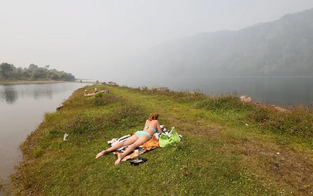 People sunbathe on a bank of the Yenisei river, which is shrouded in smoke from the Siberian Taiga wildfire, outside Krasnoyarsk, Russia, July 23, 2016. (Photo by Ilya Naymushin/Reuters)