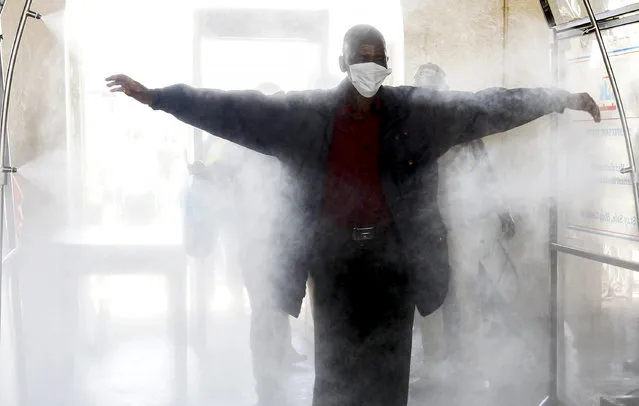 A passenger walks through a disinfectant tunnel following social distancing rules as he prepares to board the commuter train service by the Kenya Railways Corporation before a curfew, as a measure to contain the spread of the coronavirus disease (COVID-19), at the main railway station in downtown Nairobi, Kenya on April 29, 2020. (Photo by Njeri Mwangi/Reuters)