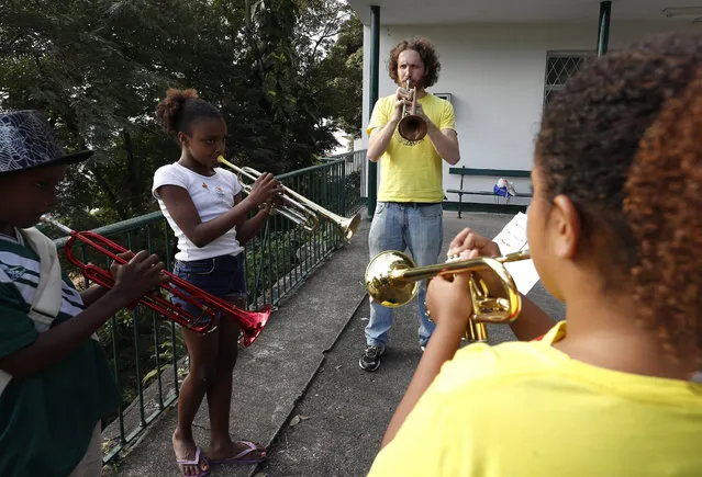 British man Tom Ashe, 36, a professional trumpet player, who founded Favela Brass plays trumpet with favela children during band rehearsals in Pereira da Silva favela, in Rio de Janeiro, Brazil, 01 August 2016. Tom's love of Brazilian live music bought him to Rio, Favela Brass will play every day in Rio neighborhoods during the Rio 2016 Olympic Games. Tom who lives in the same favela as the children started with one student in 2014 and now has 36 students, aged between 5 to 15. (Photo by Barbara Walton/EPA)