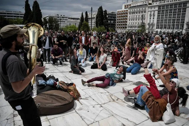 People dance and sing along Balkan music played by a band at the Syntagma square, in central Athens, on May 7, 2020 during a demonstration organised by artists, musicians and actors to ask for help to the Greek government for the financial loses due to the lockdown aimed at curbing the spread of the COVID-19, (the novel coronavirus). (Photo by Louisa Gouliamaki/AFP Photo)