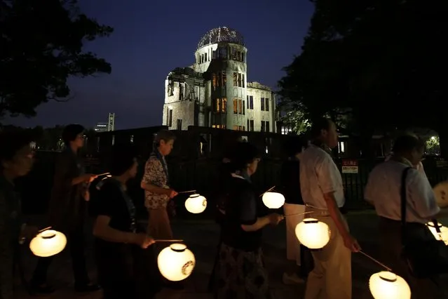 People holding paper lanterns march around the Atomic Bomb Dome (top) to comfort souls of the victims killed by the atomic bombing during World War II in 1945, at Hiroshima Peace Memorial Park in Hiroshima, western Japan, 05 August 2016. Hiroshima will mark the 71st anniversary of the world's first nuclear bombing of the city on 06 August 2016. (Photo by Kiyoshi Ota/EPA)