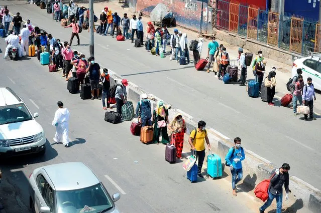 Stranded people with their belongings stand in queues to enter the railway station in New Delhi on May 12, 2020. India's enormous railway network was grinding back to life on May 12 as a gradual lifting of the world's biggest coronavirus lockdown gathered pace even as new cases surged. The country of 1.3 billion imposed a strict shutdown in late March, which Prime Minister Narendra Modi's government has credited with keeping cases to a modest 70,000, with around 2,000 deaths. (Photo by Sajjad Hussain/AFP Photo)
