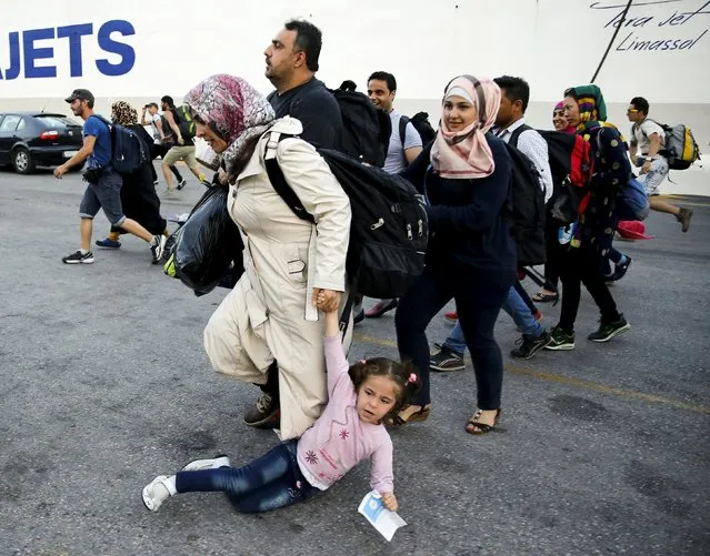 A Syrian refugee girl falls down as her family runs to buses while disembarking the Tera Jet passenger ship at the port of Piraeus, near Athens, September 9, 2015. Over the past nine days, the coastguard estimates Greek authorities have moved close to 18,000 refugees from Lesbos to the mainland. (Photo by Paul Hanna/Reuters)