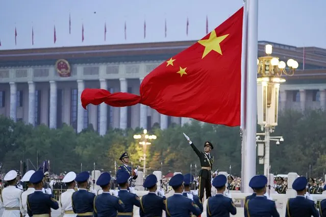 In this photo released by Xinhua News Agency, a member of the Chinese honor guard unfurls the Chinese national flag during a flag raising ceremony to mark the 73rd anniversary of the founding of the People's Republic of China held at the Tiananmen Square in Beijing on Saturday, October 1, 2022. (Photo by Chen Zhonghao/Xinhua via AP Photo)