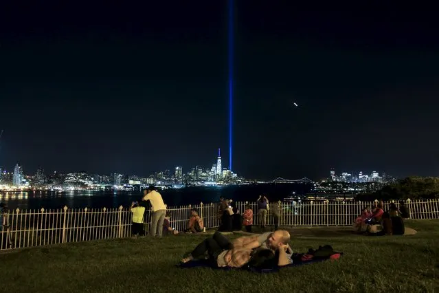 The Tribute in Light is illuminated next to the One World Trade Center while people enjoy the view along the Hudson River during events marking the 14th anniversary of the 9/11 attacks on the World Trade Center in New York September 11, 2015. (Photo by Eduardo Munoz/Reuters)