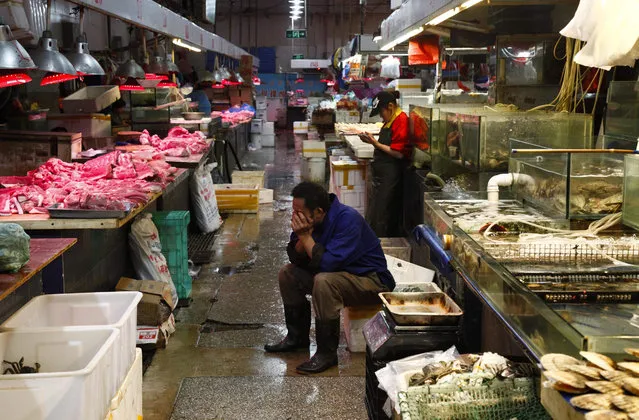 A Chinese vendor takes a rest amid stalls of meat and seafood at a public market in Beijing, China, 11 September 2015. Consumer inflation in China reached its highest point for a year as consumer price index was up 2 per cent year-on-year in August, while the producer price index was down 5.9 per cent and indicated the biggest drop in more than five years, the National Bureau of Statistics (NBS) said on 10 September. (Photo by Rolex Dela Pena/EPA)